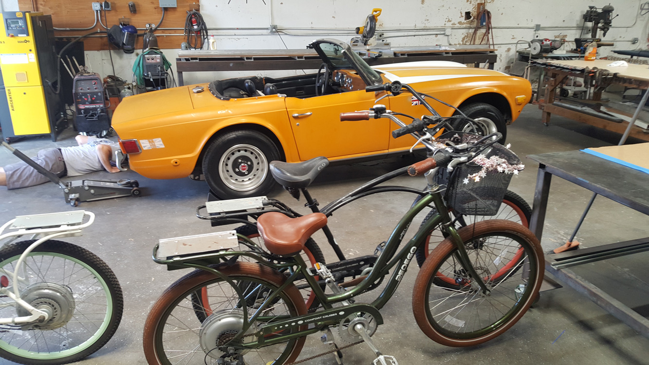 Pedego bikes sitting in front of a classic car.