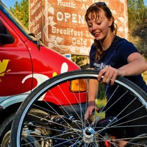 Woman fixing a wheel on a Pedego electric bike.