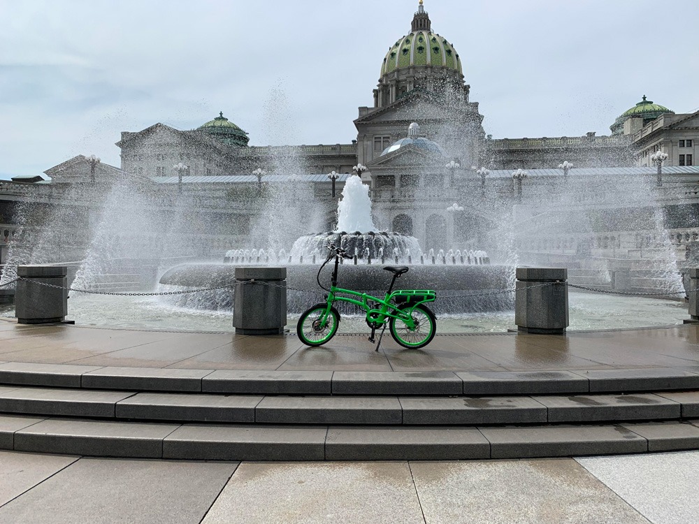 Pedego Latch bike in front of a fountain.