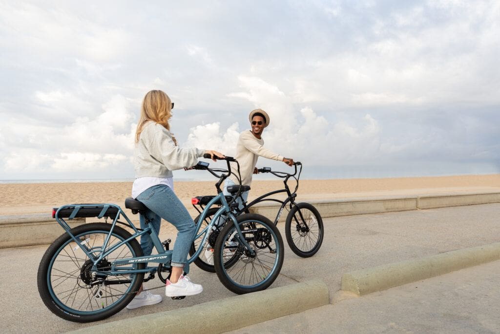 A couple enjoying a ride on the boardwalk on thei Pedego Interceptor Cruiser Electric Bike
